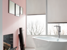 Bañera ovalada independiente de acero esmaltado en baño moderno con azulejos imitación madera y mucha luz natural.